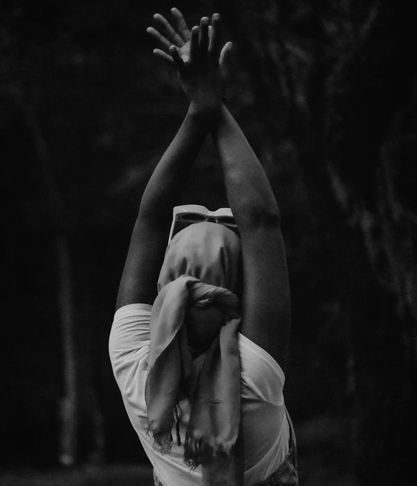 Woman in a calming yoga pose against a dark background.